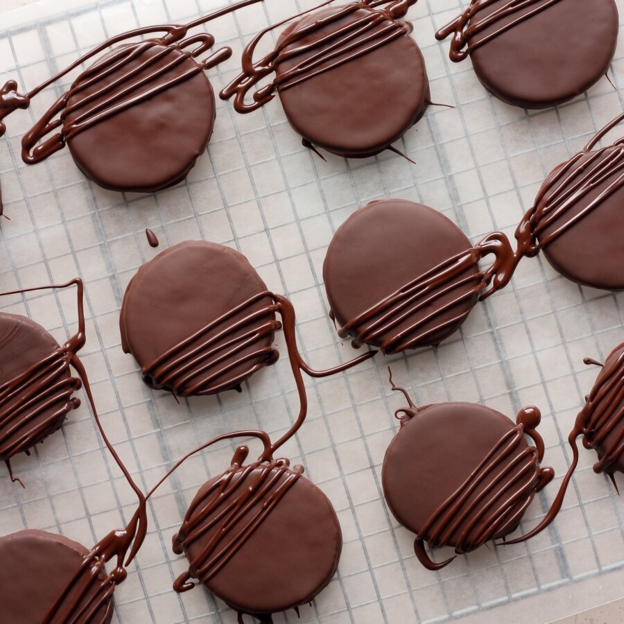 Thin mint cookies on a wire cooling rack on a pink backdrop