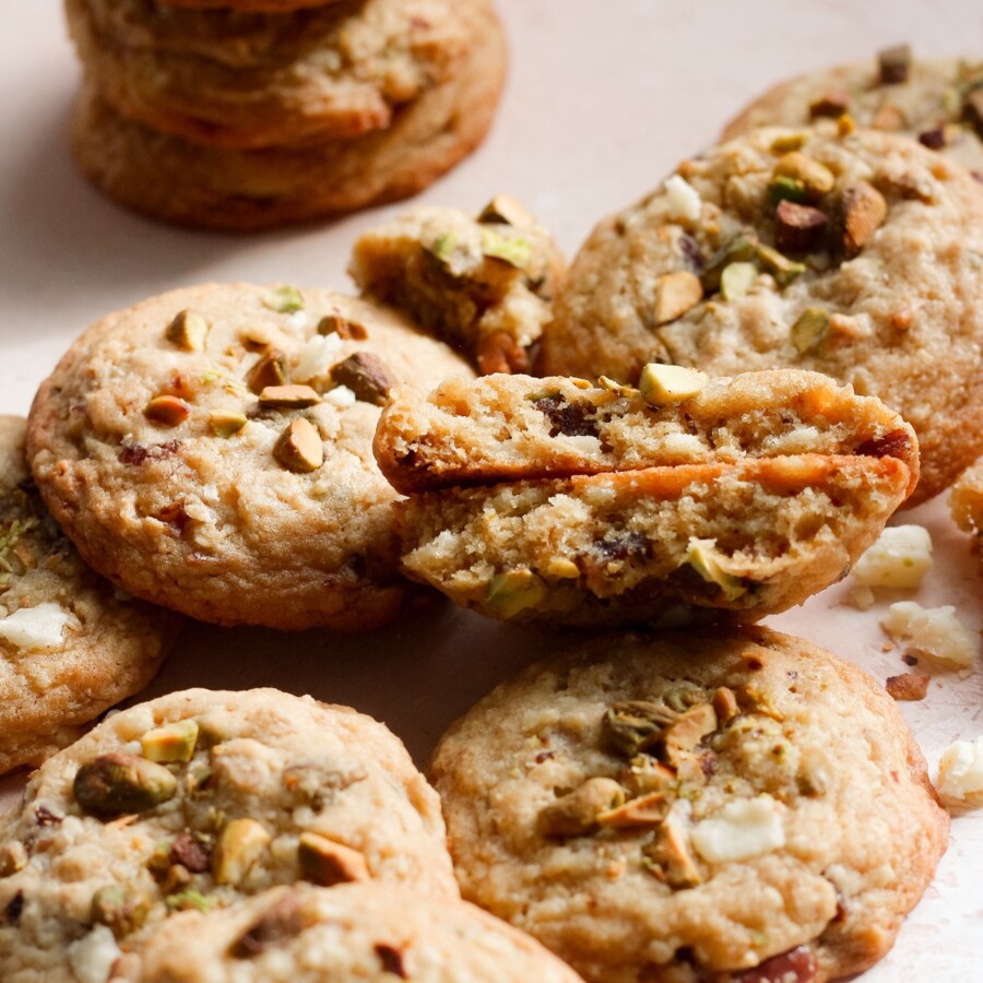 Cheddar pistachio cookies on a pink backdrop.