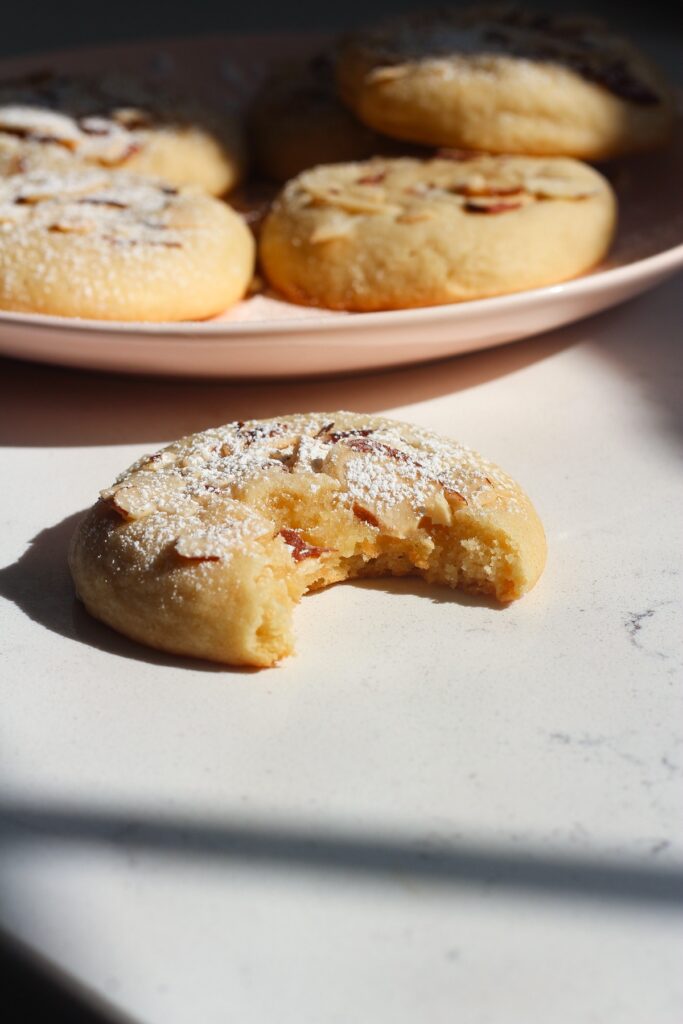 Almond cookie on a white counter next to a pink plate