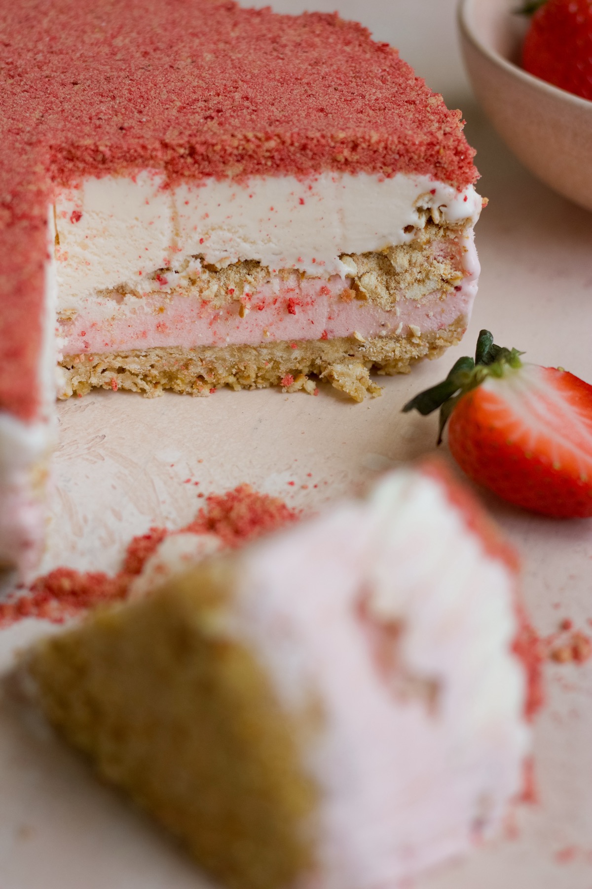 Strawberry crunch ice cream cake on a pink backdrop