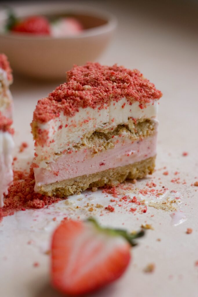 Strawberry crunch ice cream cake on a pink backdrop.