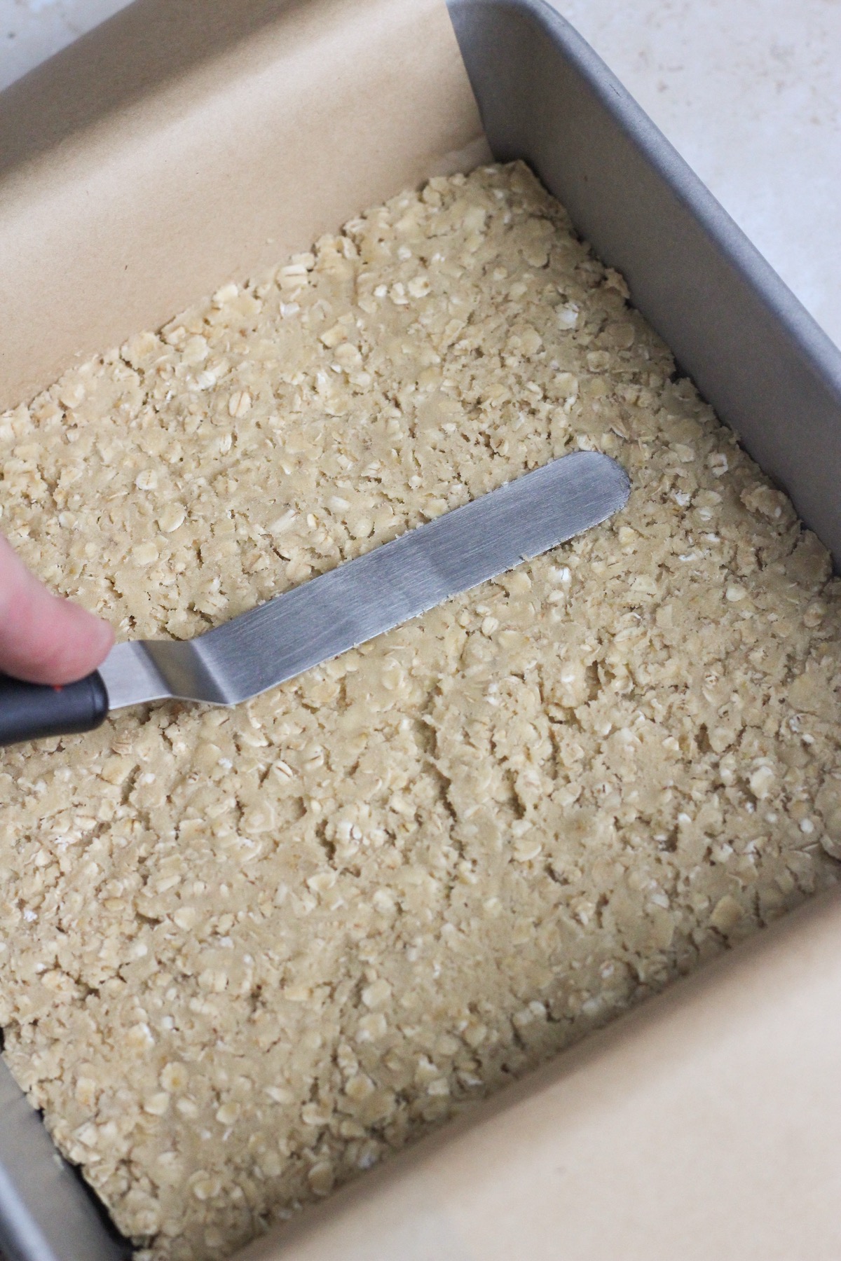 Chocolate revel bars in a pan on a tan backdrop