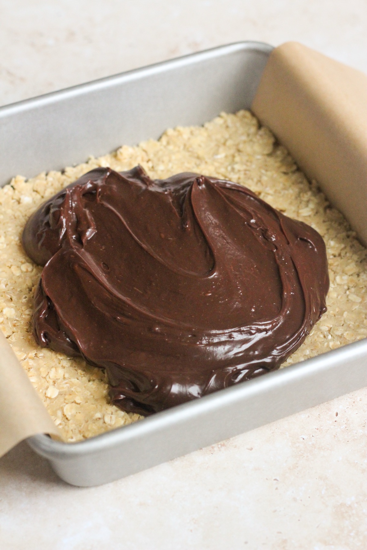 Chocolate revel bars in a pan on a tan backdrop