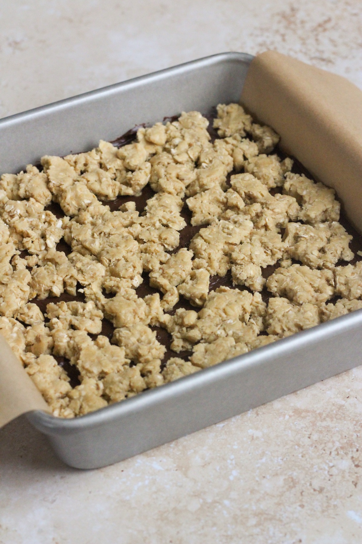 Chocolate revel bars in a pan on a tan backdrop