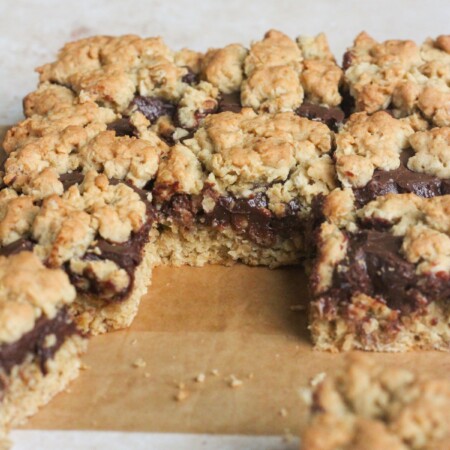 Close up shot of chocolate revel bars in a pan on a tan backdrop.