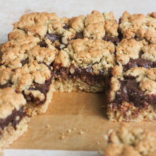 Close up shot of chocolate revel bars in a pan on a tan backdrop