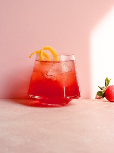 Summer Spritz cocktail on a pink backdrop with a strawberry.