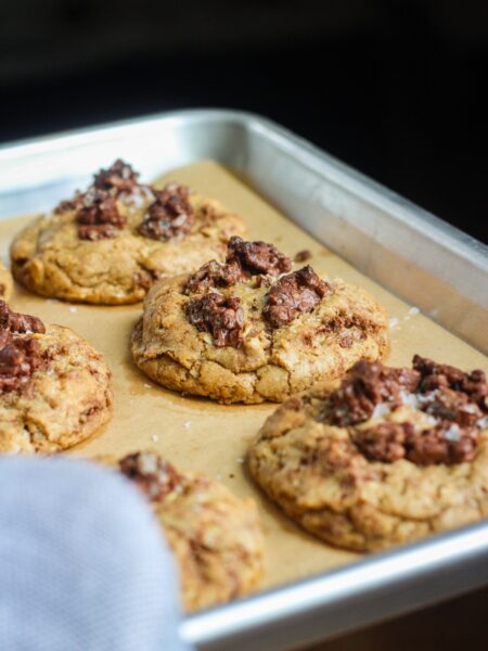 Tray of baked chocolate crunch cookies and an oven mitt.