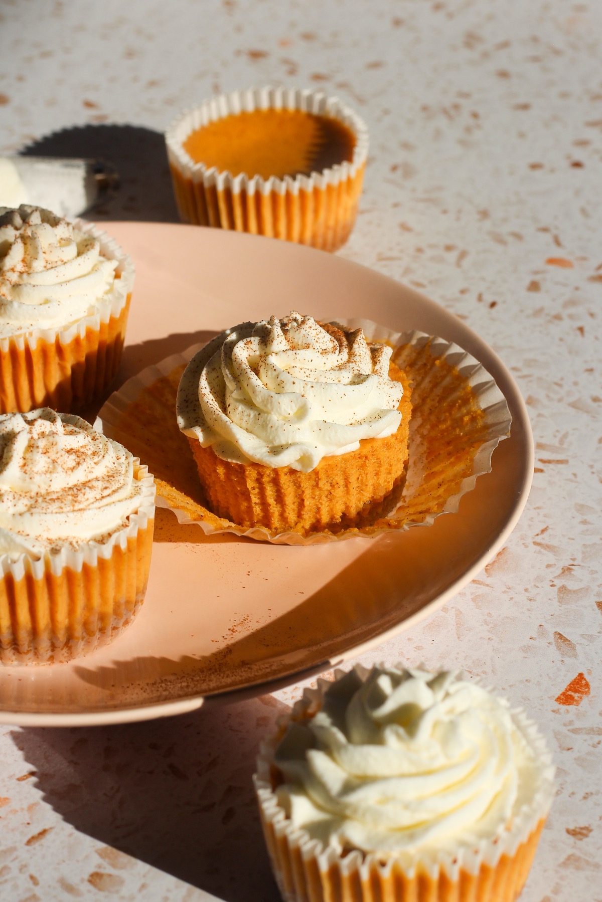 Mini pumpkin cheesecakes on a pink plate.
