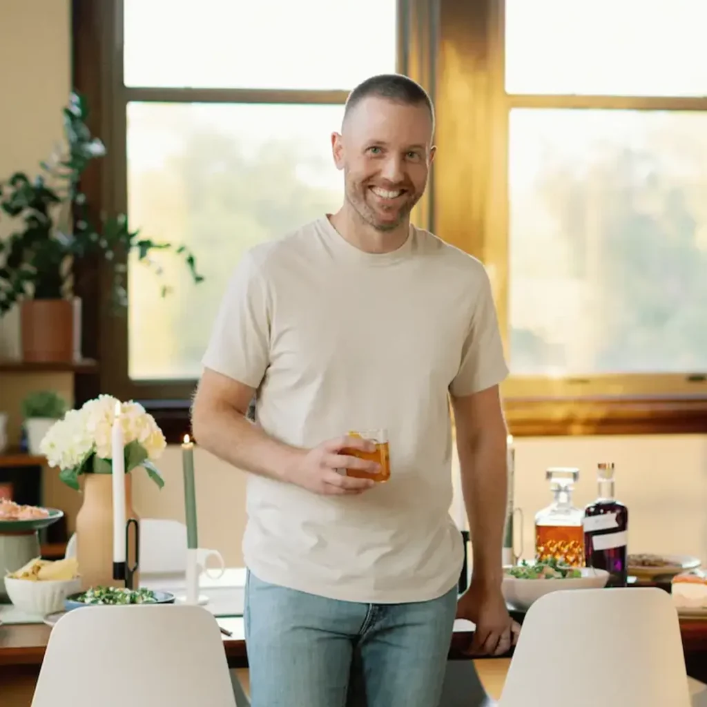 Tyler, author of Schmidty Bakes, standing at dinner table with a drink in hand.