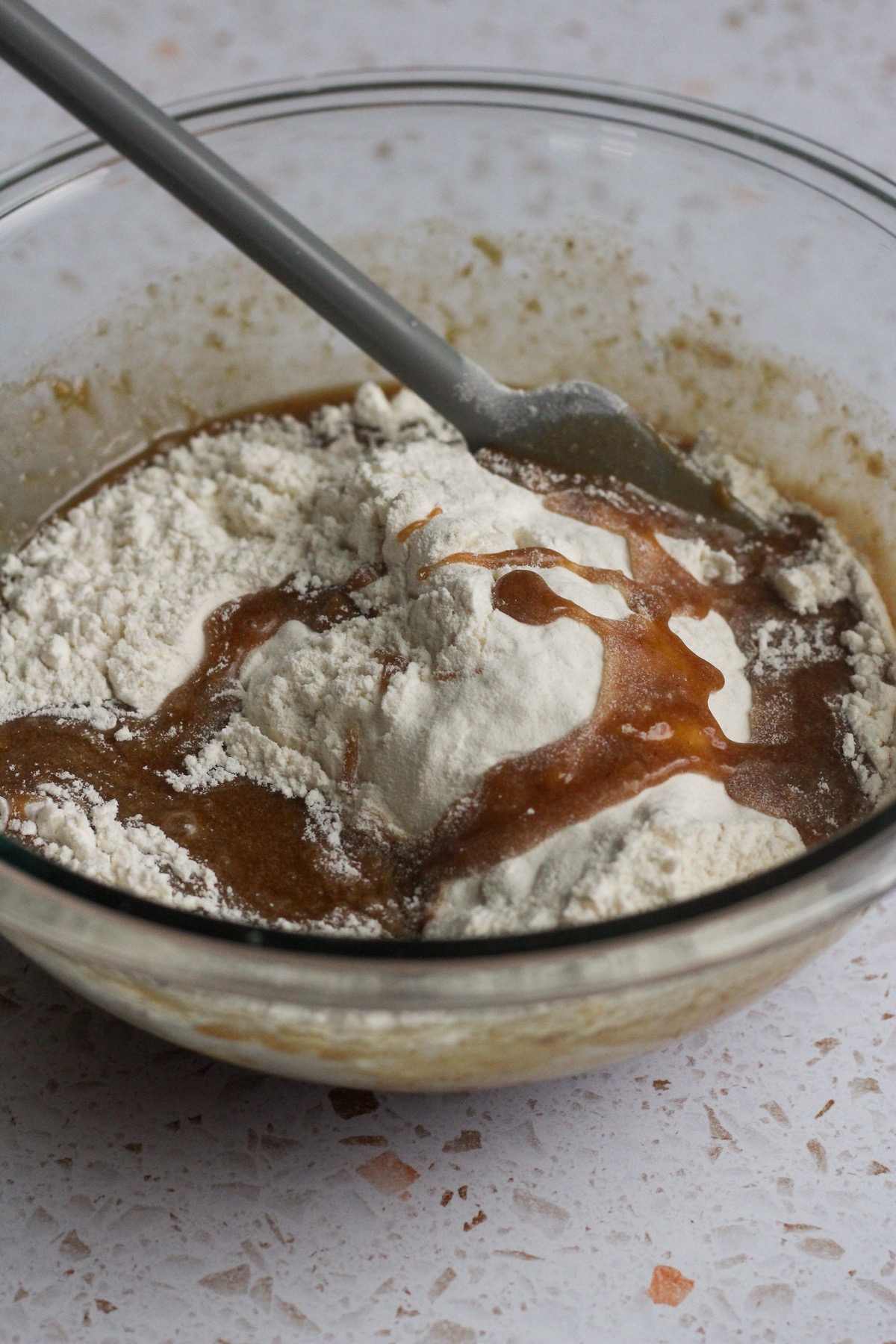 Banana chocolate chip cookie dough mixture dry ingredients on top in a glass bowl.