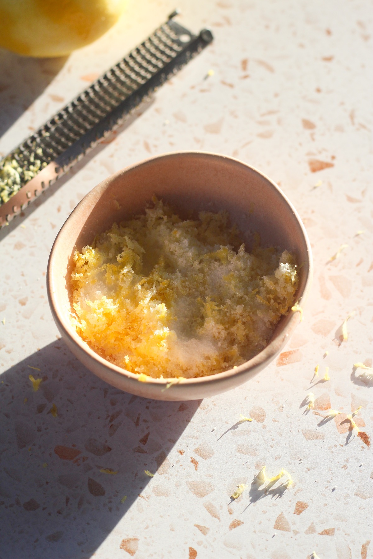 Lemon zest and granulated sugar in a pink bowl.