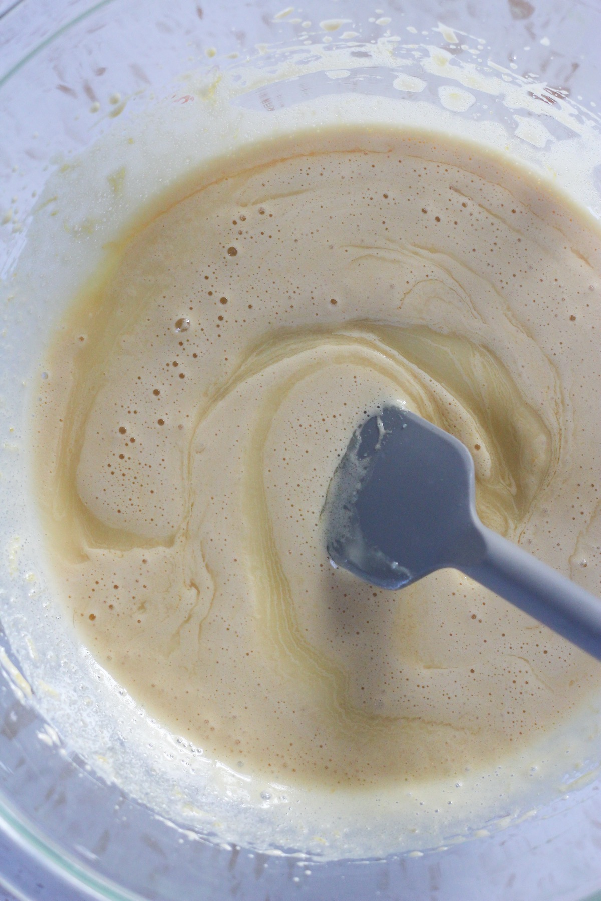 White chocolate and butter mixture being swirled into egg and sugar mixture.