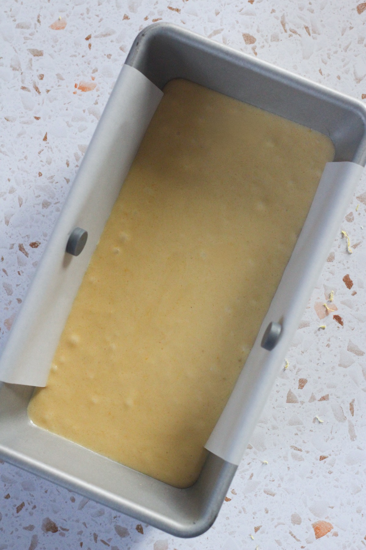 Lemon brownies batter in a 9x5 pan lined with parchment paper.