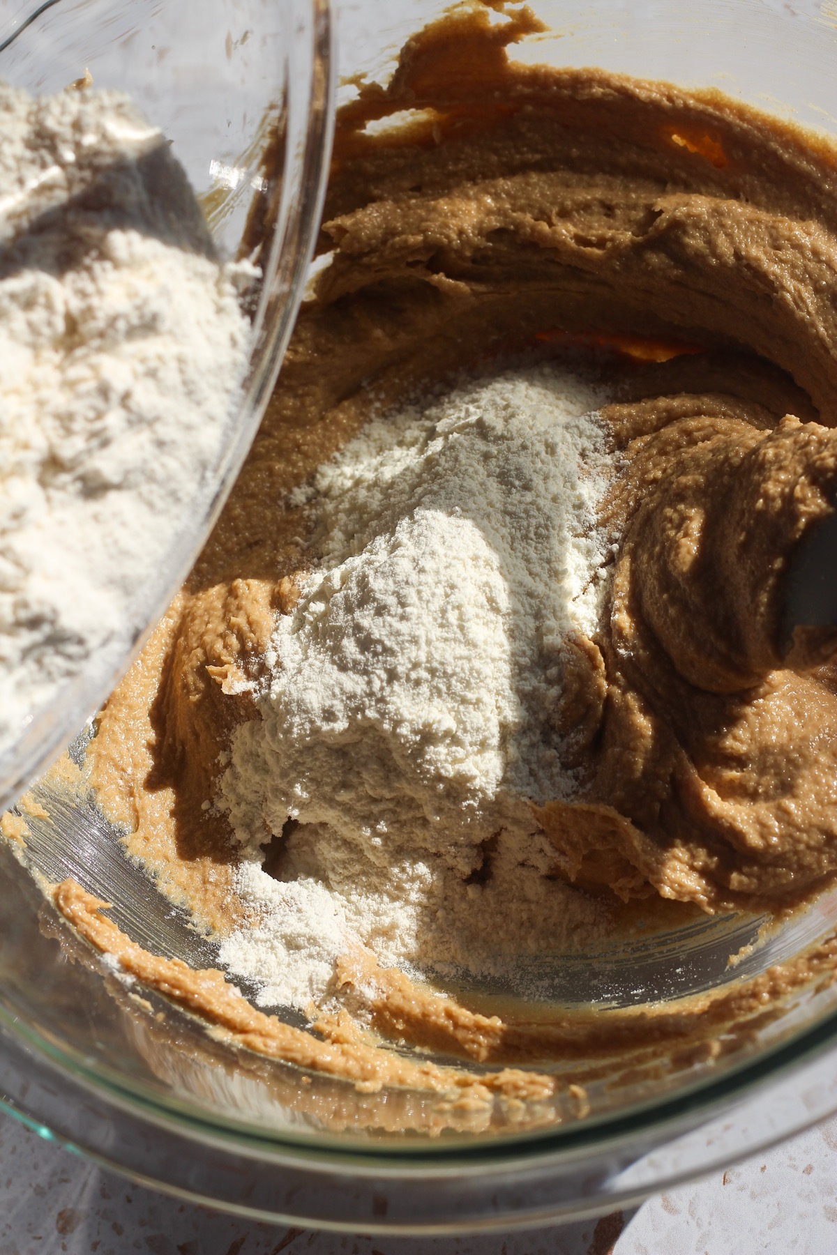 Dry ingredients being added to the wet ingredients of peanut butter blossoms.