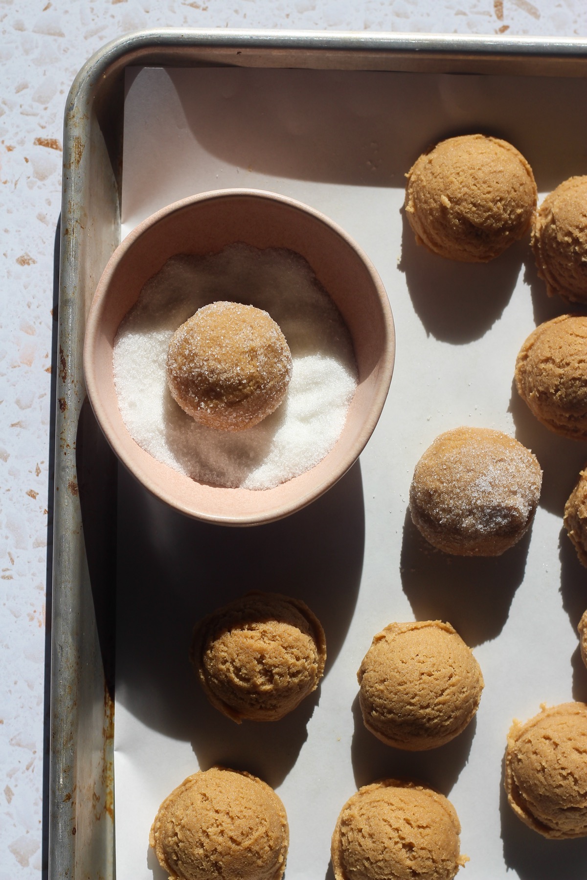 Peanut butter blossoms being rolled in sugar coating.