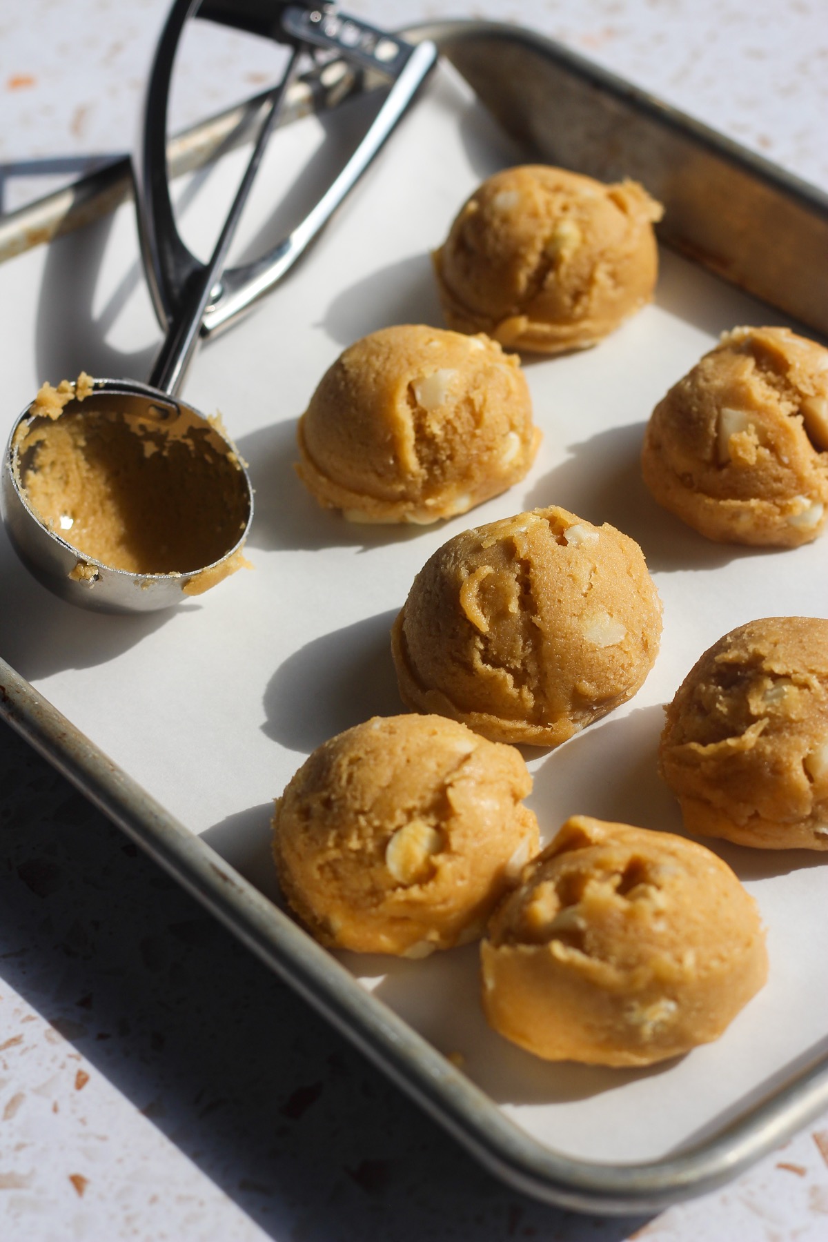 White chocolate macadamia nut cookies scooped on a baking sheet.