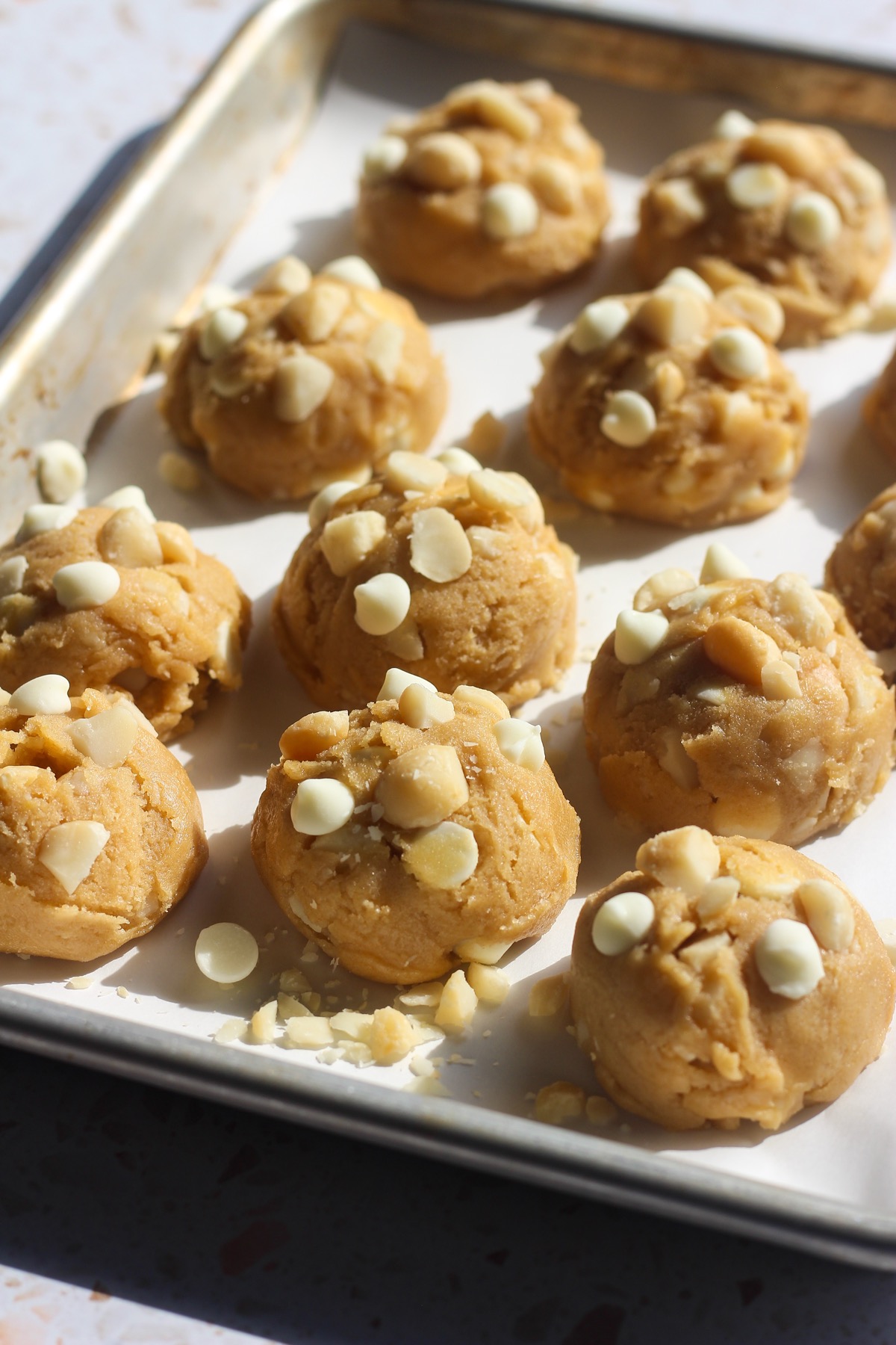White chocolate macadamia nut cookie dough on a baking sheet.