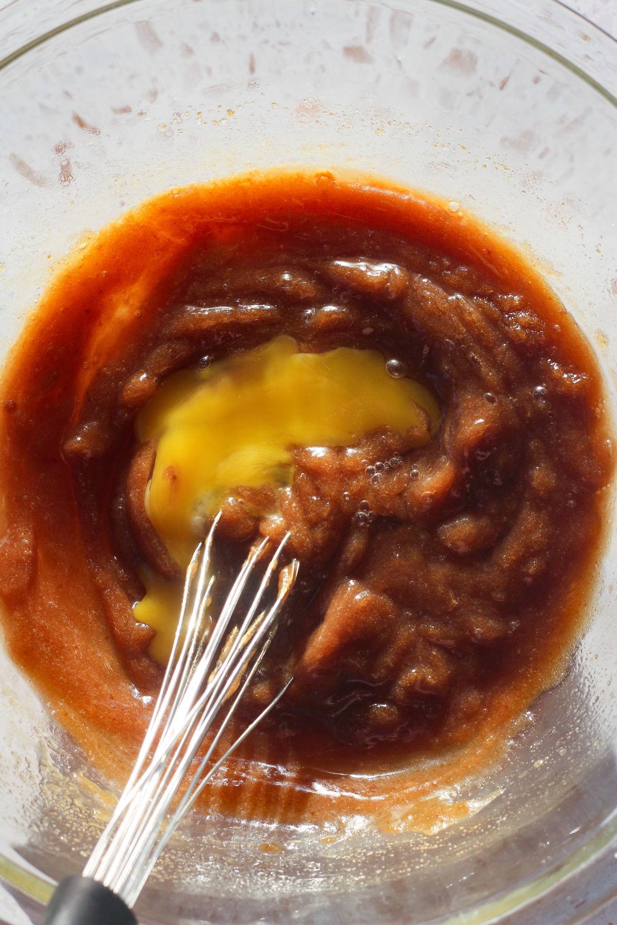 Egg being whisked into brown sugar and browned butter mixture