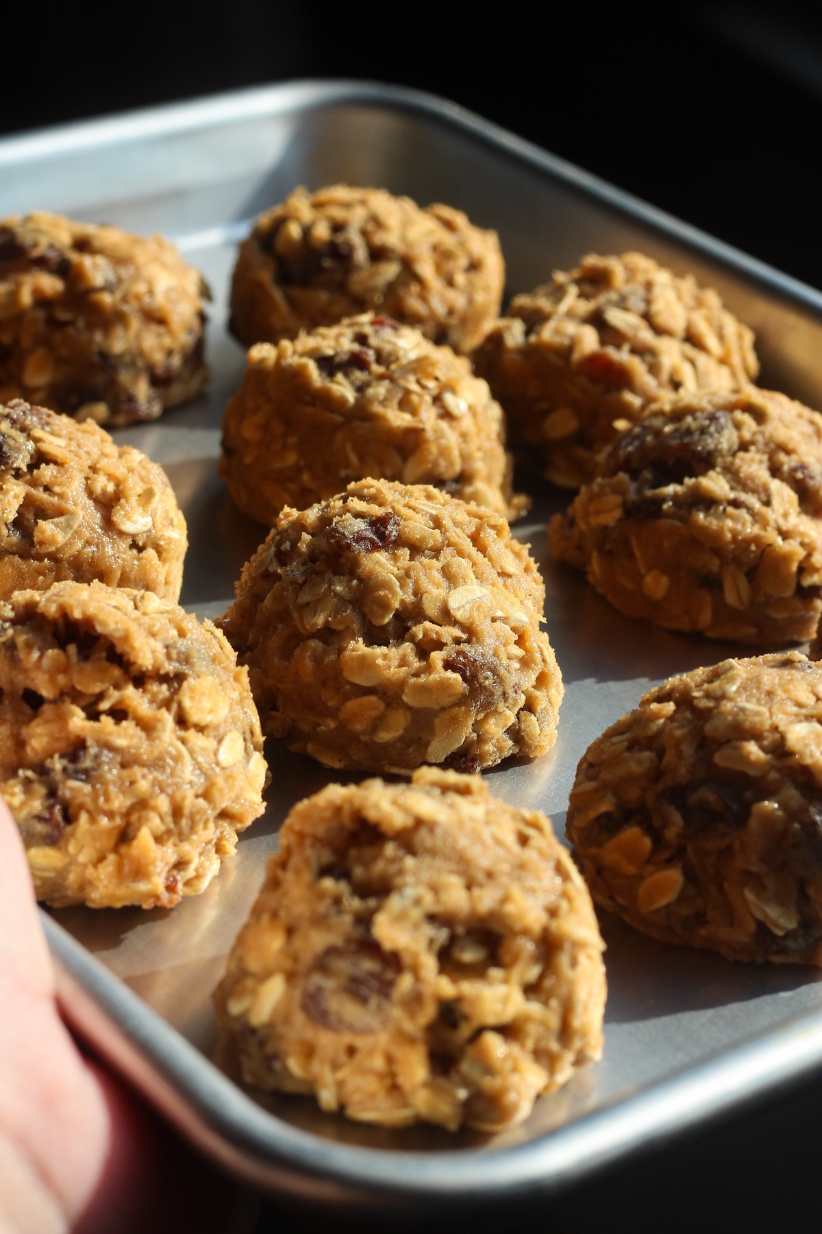 Scooped oatmeal raisin cookie dough balls on a baking sheet before chilling
