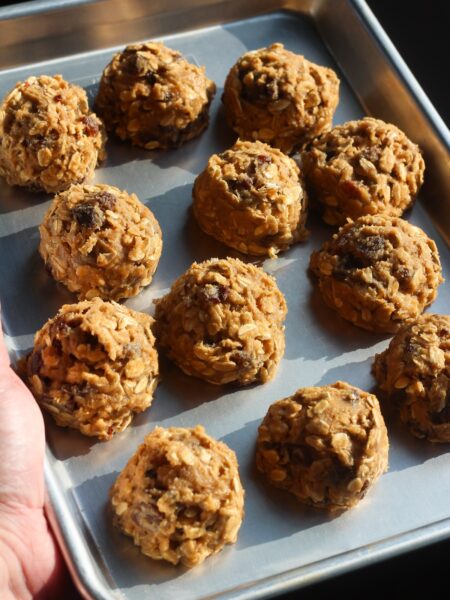 Chilled oatmeal raisin cookie dough balls ready to bake on a metal sheet pan