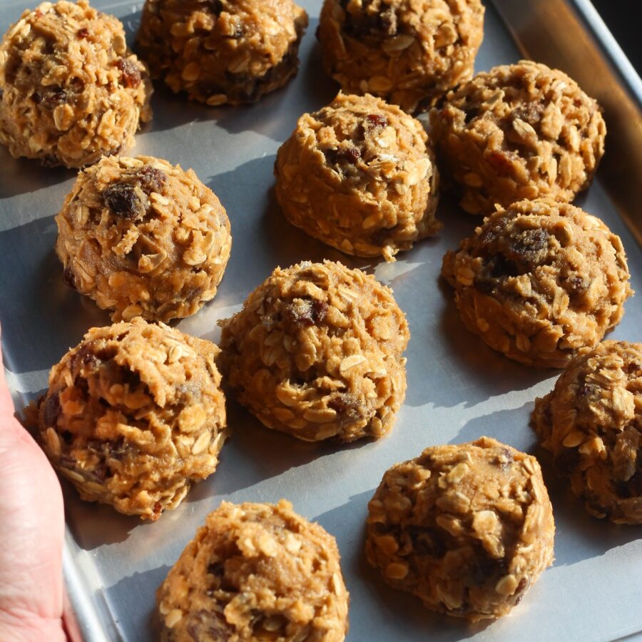 Chilled oatmeal raisin cookie dough balls ready to bake on a metal sheet pan