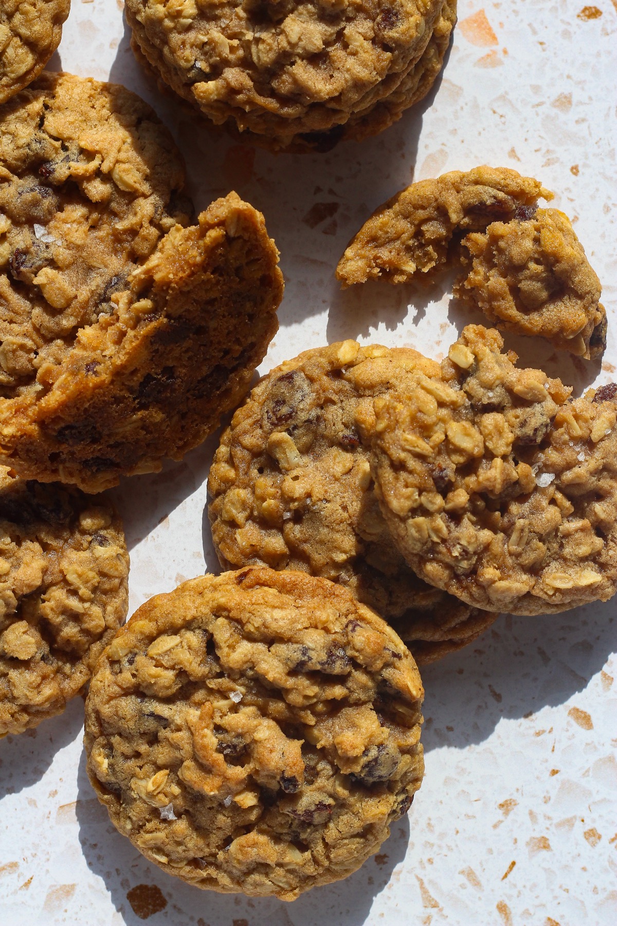Overhead view of baked oatmeal raisin cookies with one broken in half